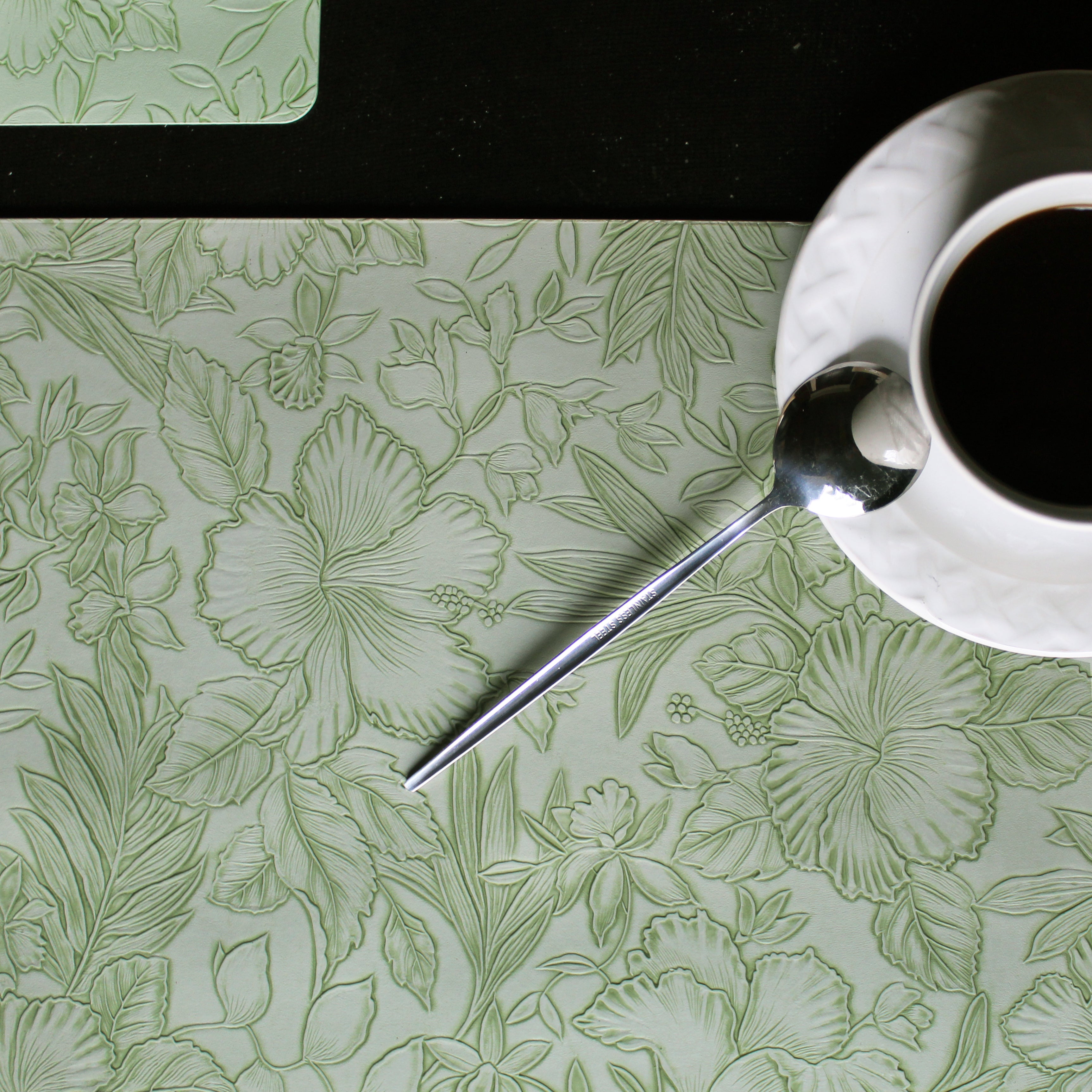 Mantel individual rectangular de piel sintética con patrón de flores disponible en verde, gris y rosa claro.